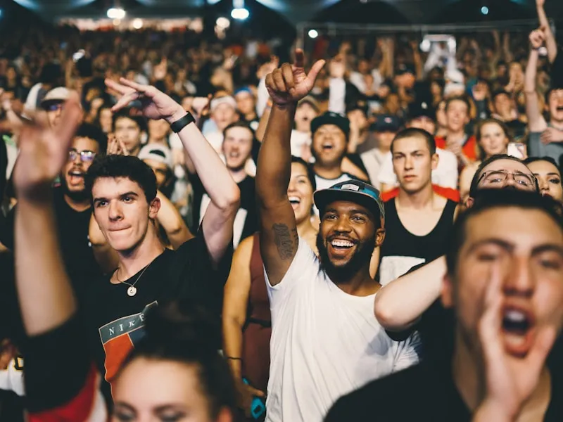 Hands raised in a packed concert crowd bathed in blue stage light