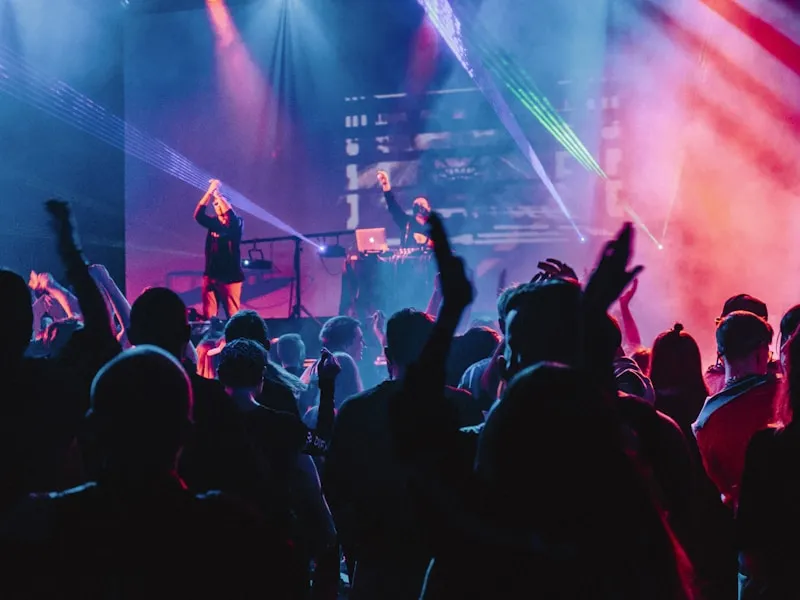 DJ performing on stage with dramatic lighting behind the decks